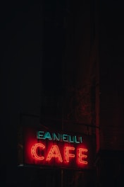An elegant LED sign mounted outside a bustling café at dusk.