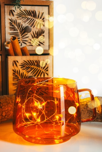 A warm amber bottle illuminated with tiny fairy lights, surrounded by autumn leaves.