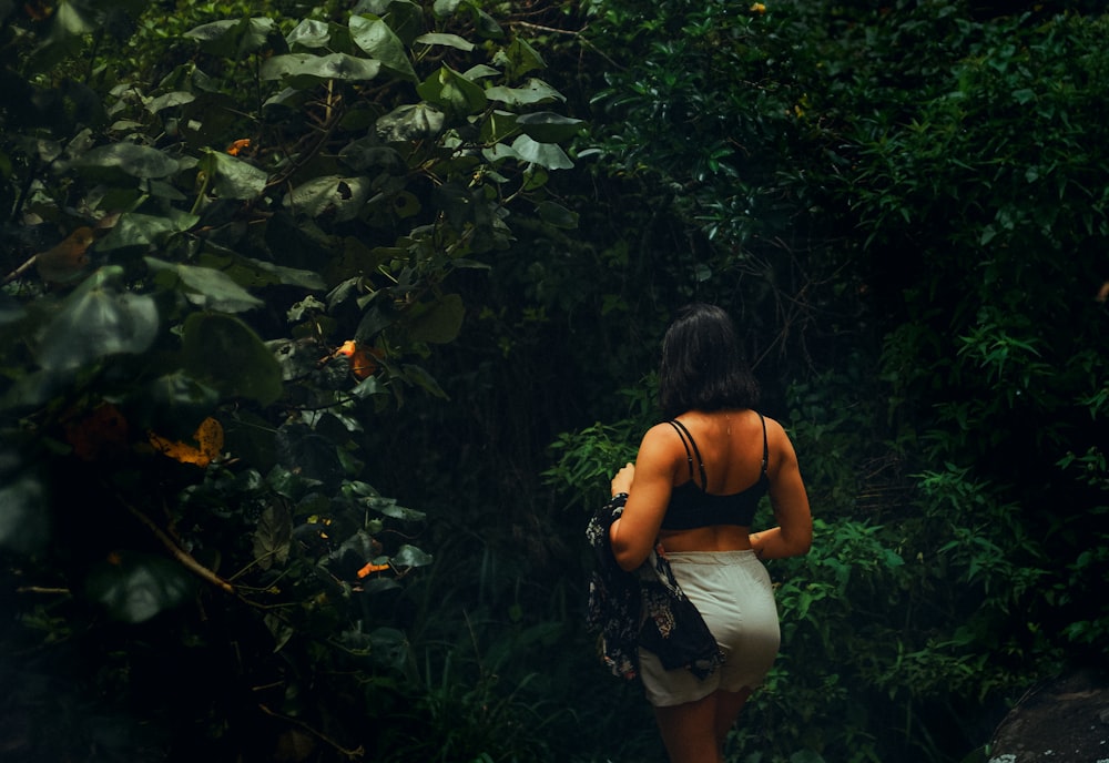 a woman in a white skirt walking through a forest