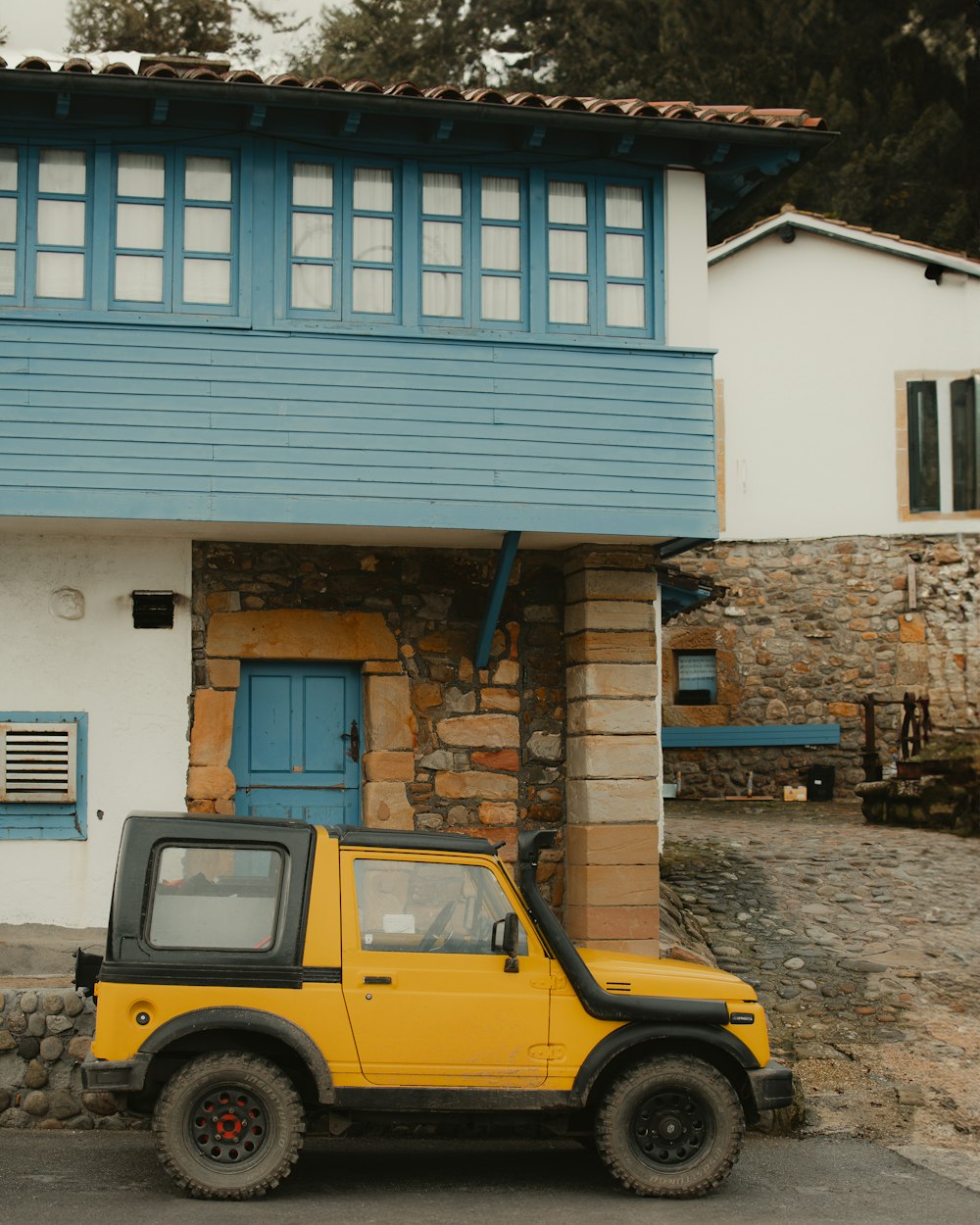 a yellow jeep parked in front of a house