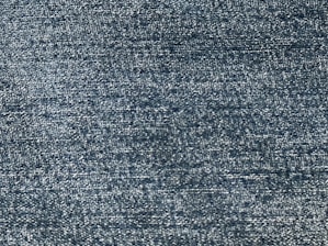 A close-up view of a textured fabric, showing a pattern of tightly woven threads with a consistent blue tone.