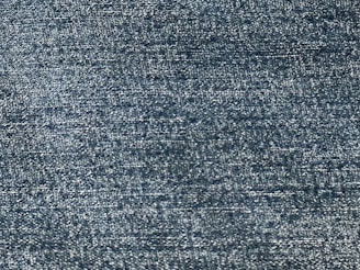 A close-up view of a textured fabric, showing a pattern of tightly woven threads with a consistent blue tone.