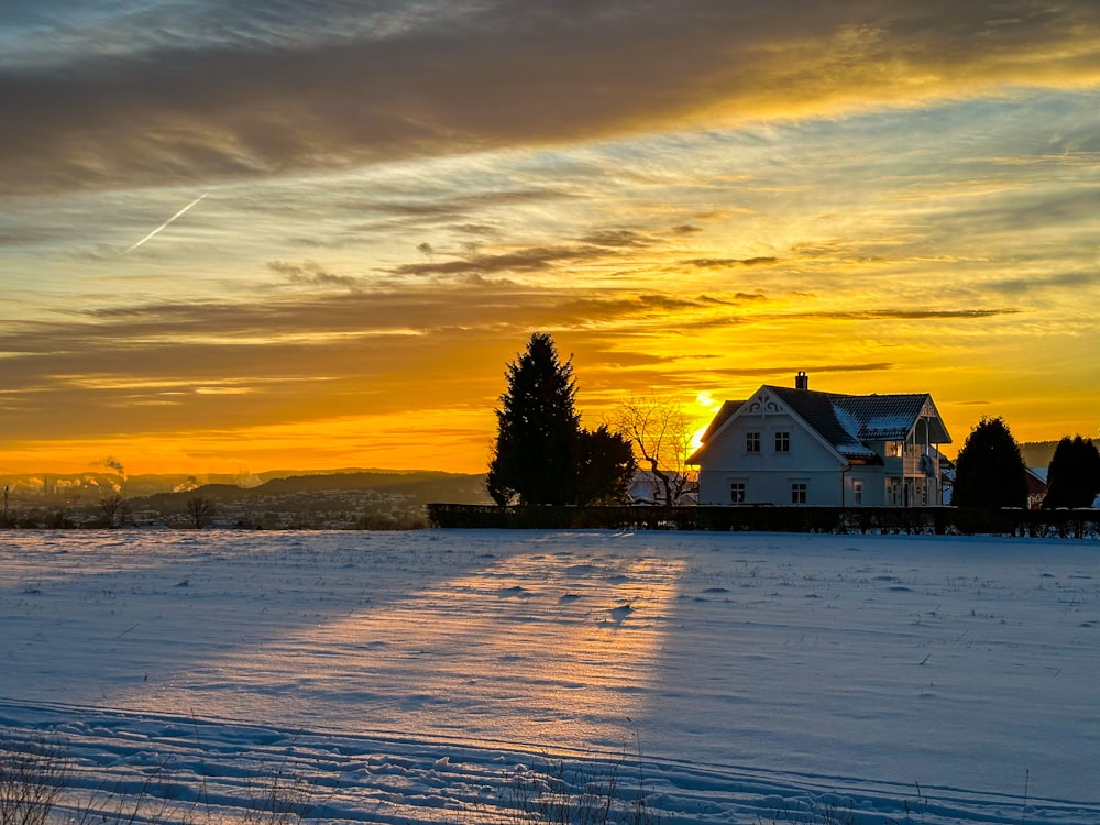 a snow covered field with a house in the background