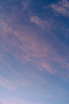 Soft clouds with a pink hue float across a blue sky, suggesting the gentle transition of a sunset or sunrise.