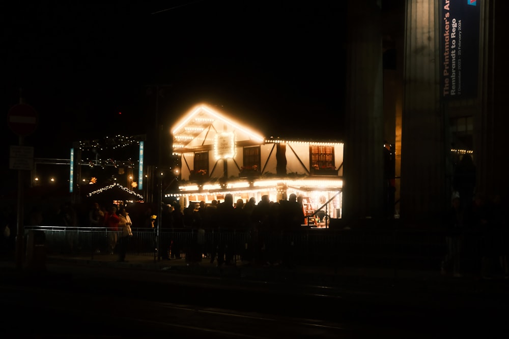 a group of people standing outside of a building at night