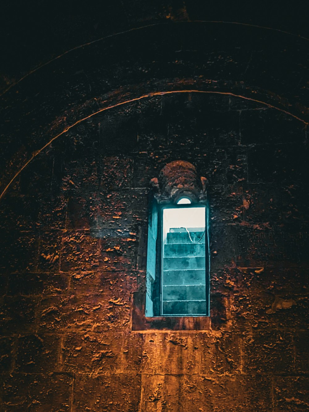 una ventana en una pared de piedra con una luz que entra a través de ella