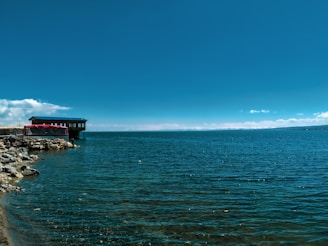 A serene lakeside cabin reflecting perfectly on calm water under a clear blue sky