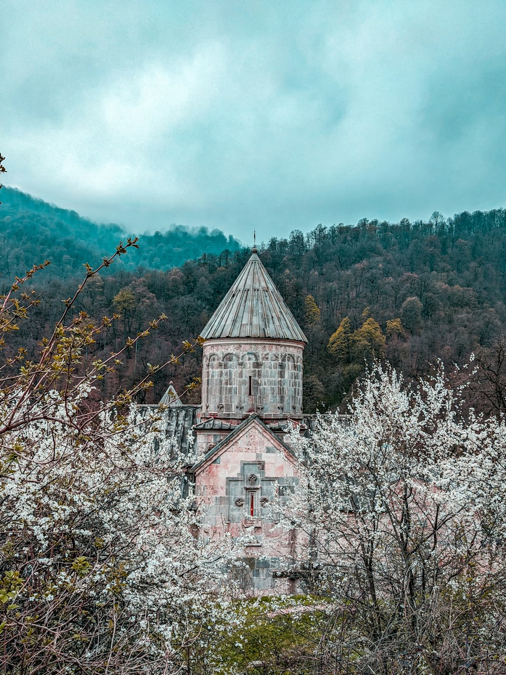 un vieux bâtiment avec un clocher entouré d’arbres