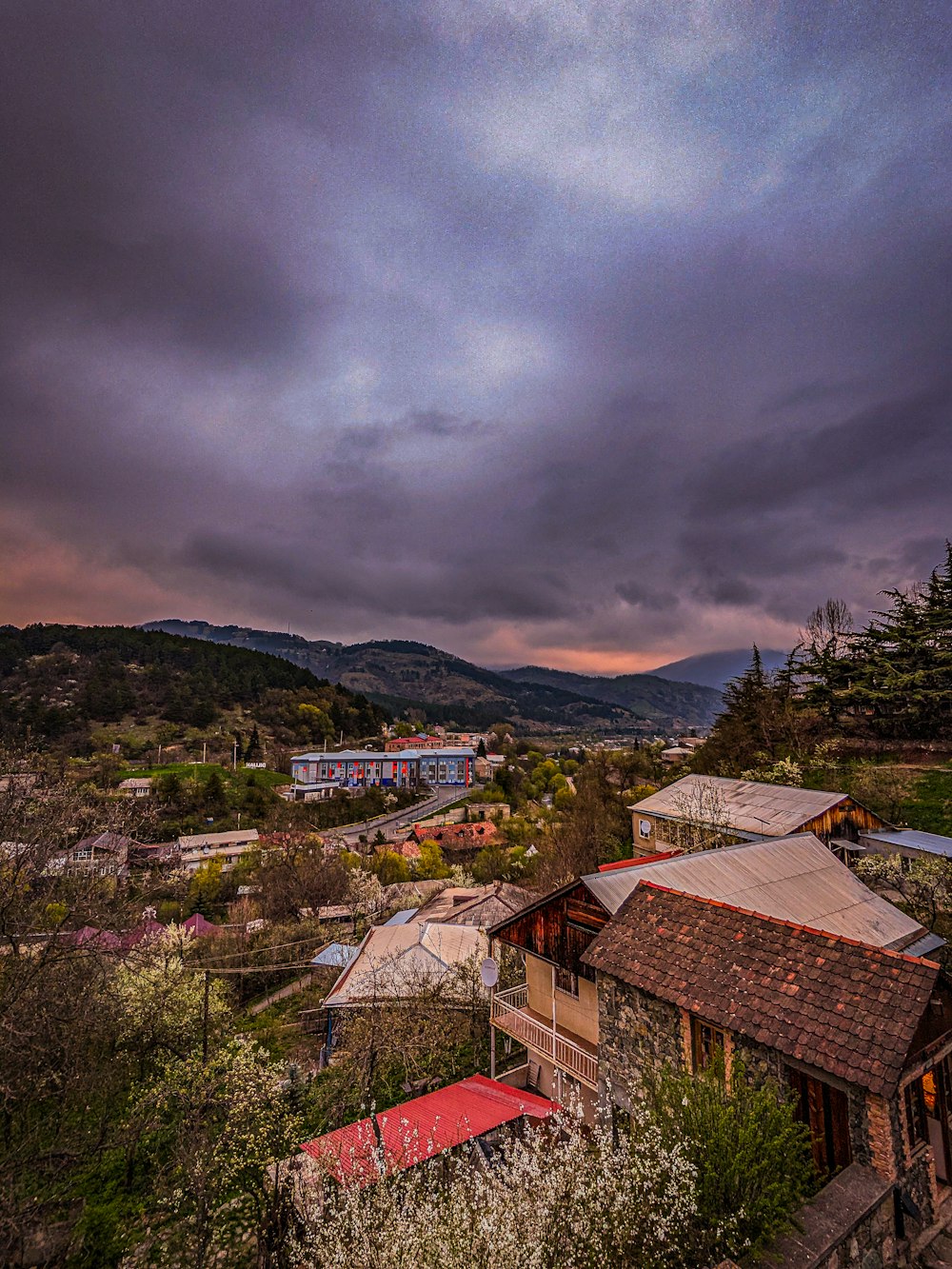 a cloudy sky over a small town with mountains in the background
