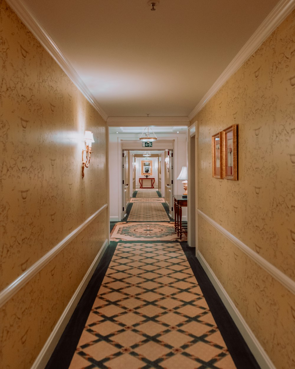 a long hallway with a checkered carpet and two lamps