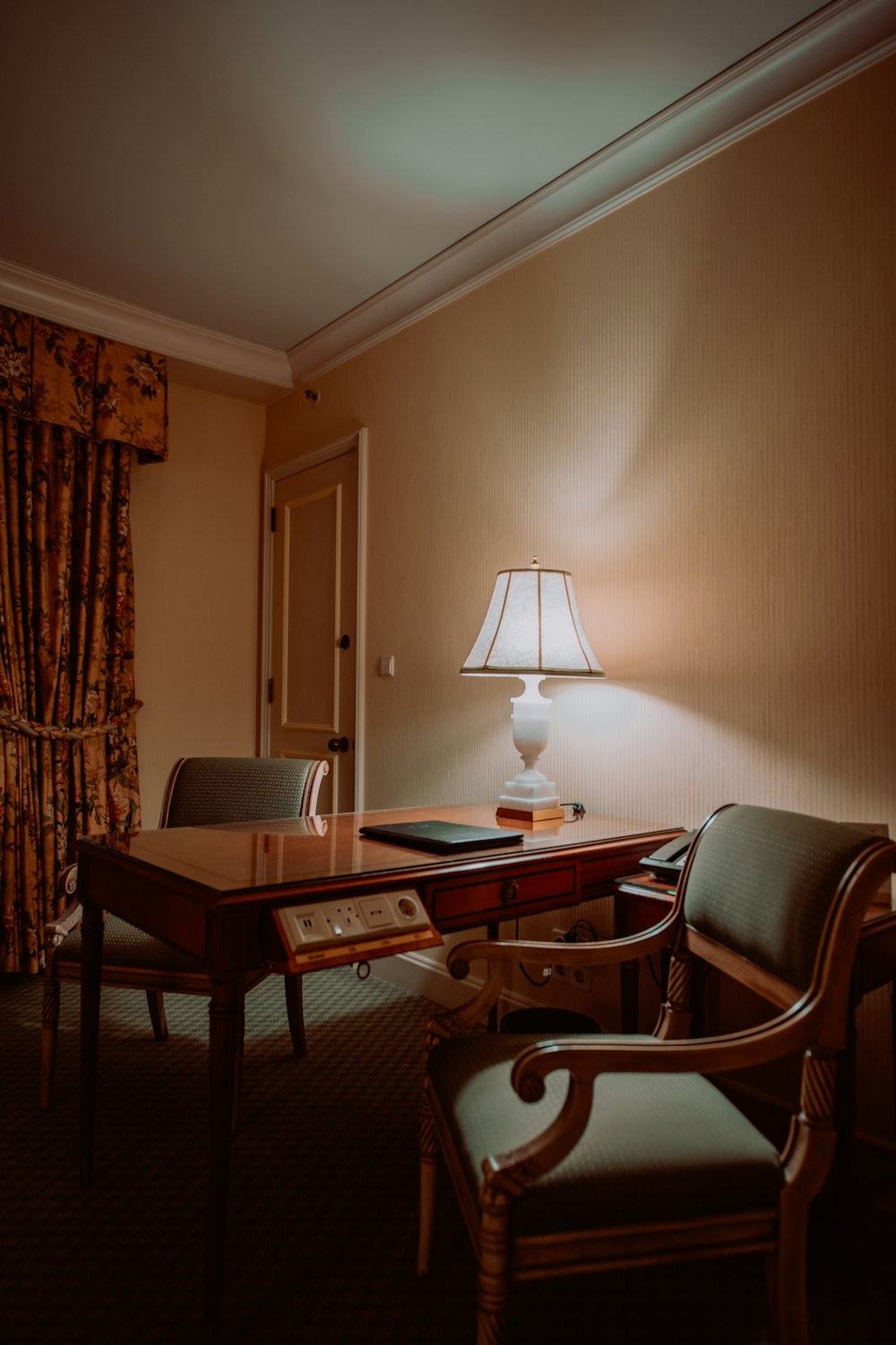 une chambre d’hôtel avec un bureau, une chaise et une lampe