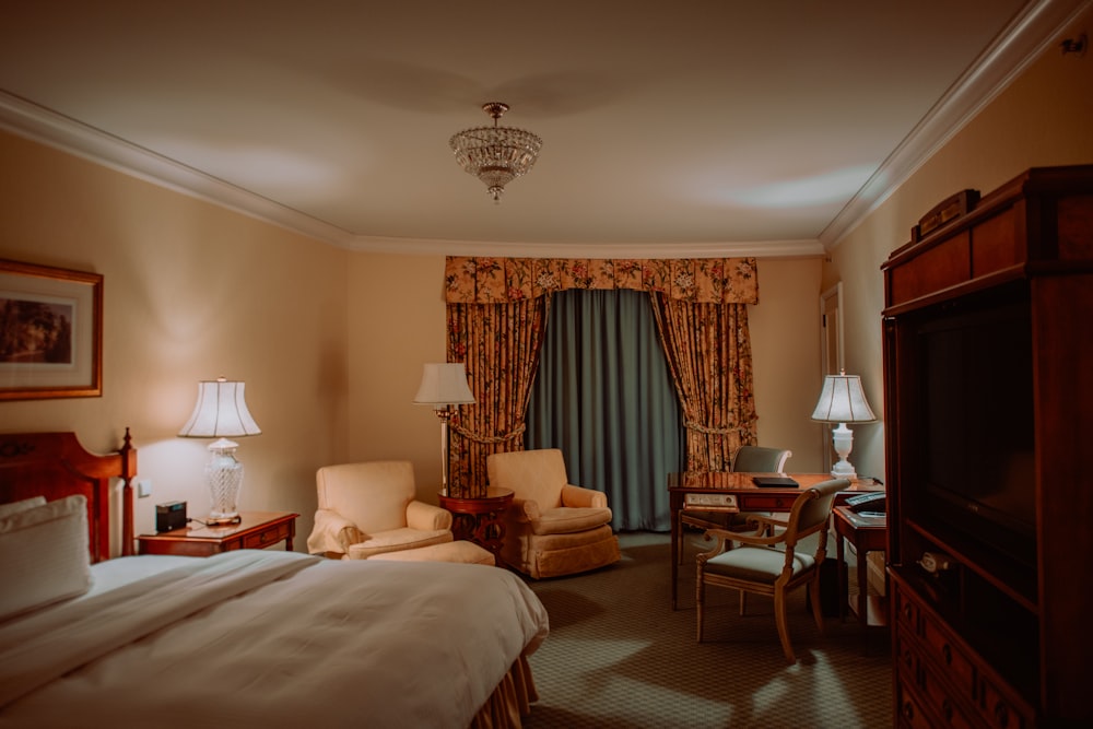 a hotel room with a bed, chair, desk and television