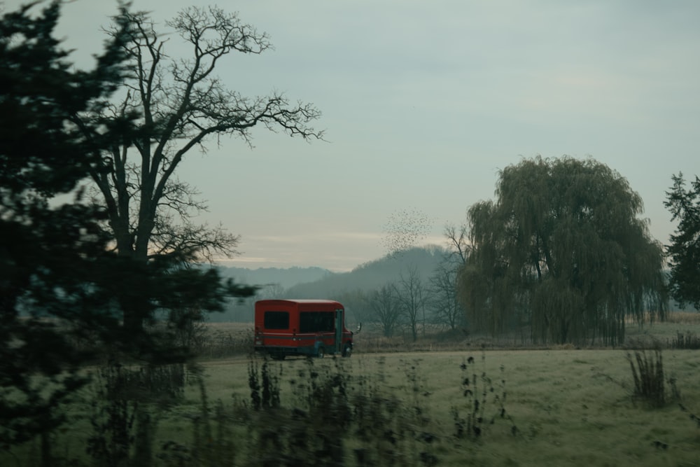 a red truck parked in a field next to a tree