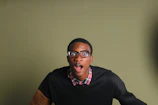 A screenshot of a prank video showing a surprised reaction in a green and blue themed room.