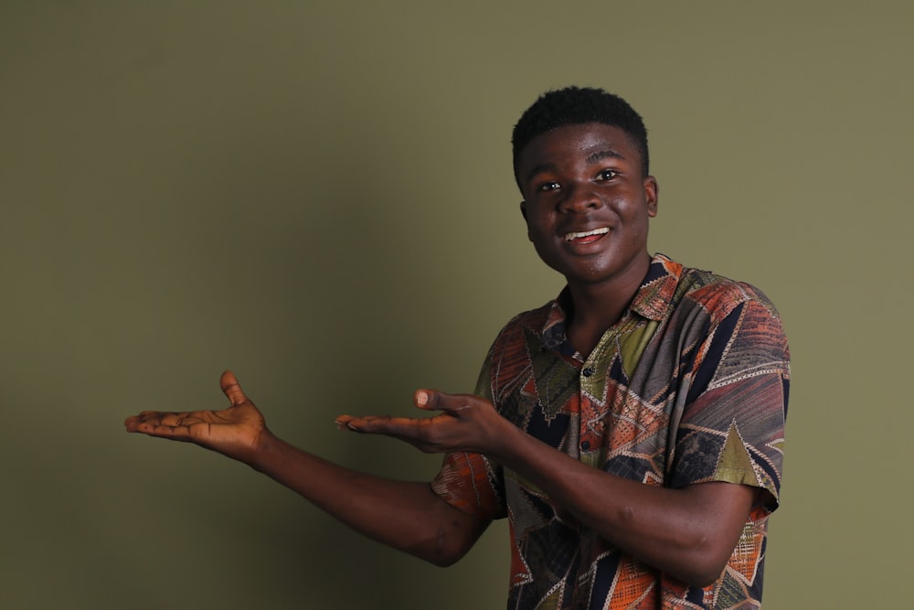 a man holding out his hands in front of a green wall