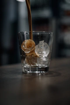 Close-up of fresh ice pouring from aguamax machine into a clear cup on a sunny day.