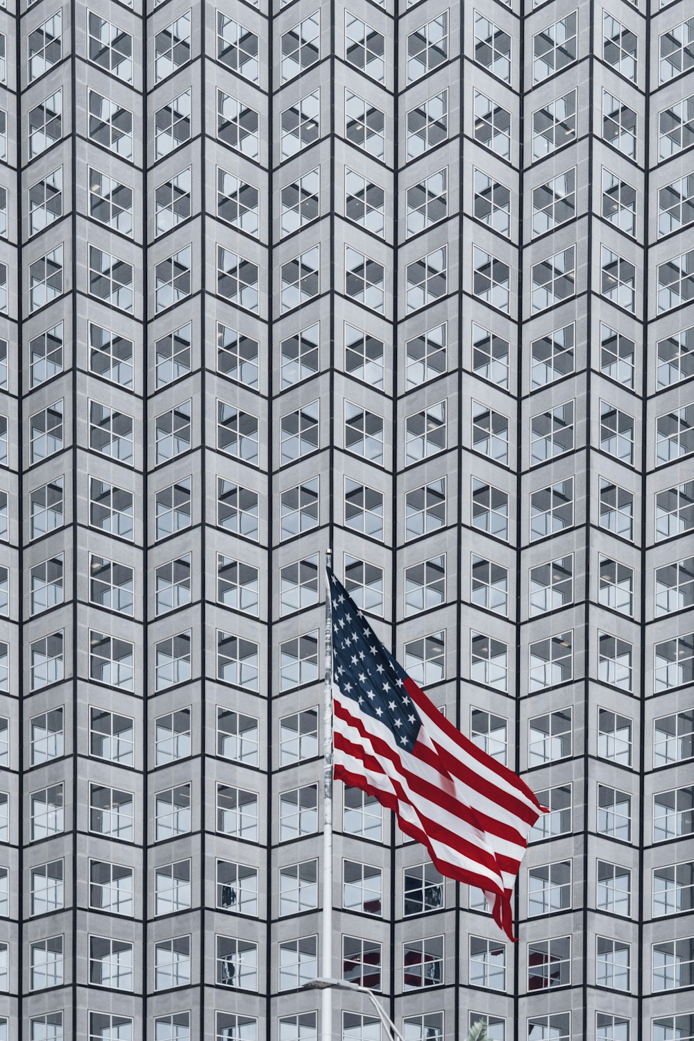 a large american flag flying in front of a tall building