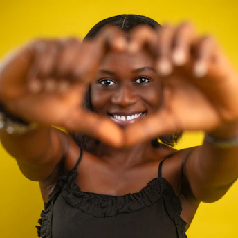 A joyful woman smiling warmly while holding a glowing heart symbol, radiating confidence.