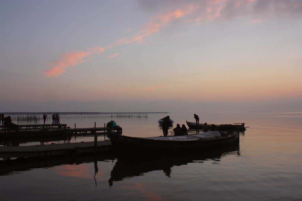 a group of people standing on a dock next to a boat