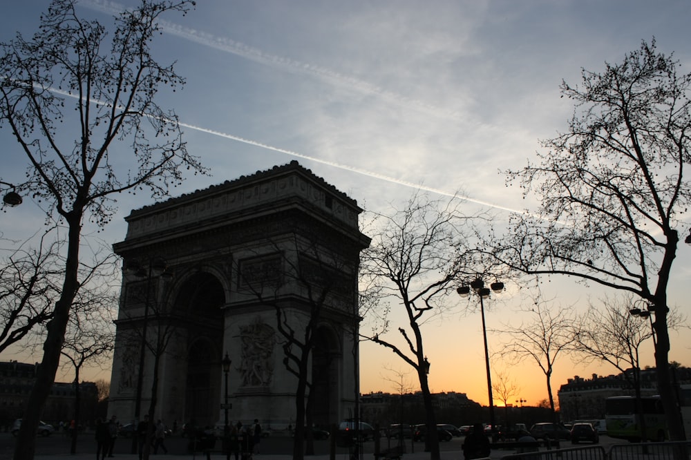 the sun is setting behind a monument in a park