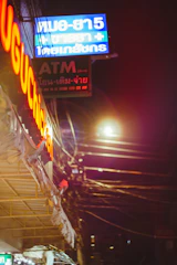 A neon pink accented card showing ไทย in native script with a glowing dot.