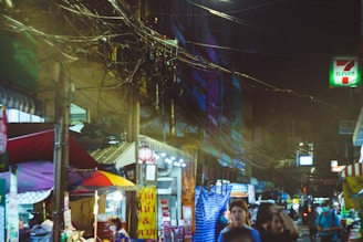 A bustling Bangkok street market glowing with colorful lights at dusk.