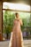 A stylish woman wearing elegant linen clothing, standing in a sunlit room with soft textures and neutral colors.