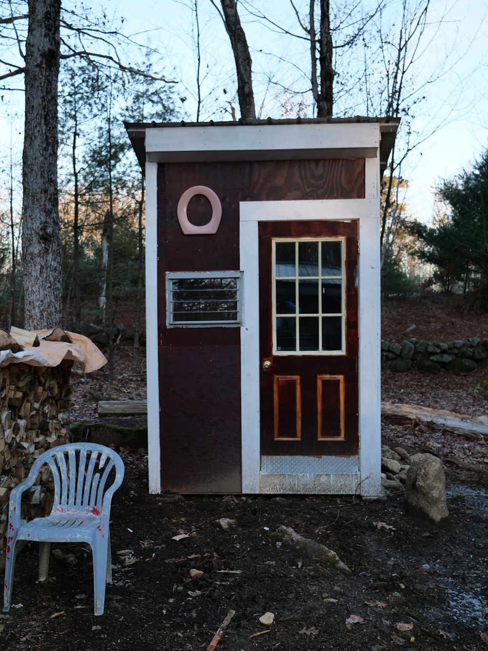 a white chair sitting next to a small outhouse