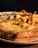 A plate of comfort food featuring a sandwich topped with melted cheese and garnished with parsley. Accompanying the sandwich are crispy golden fries and a side salad with lettuce, cucumber, and a drizzle of dressing.