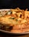 A plate of comfort food featuring a sandwich topped with melted cheese and garnished with parsley. Accompanying the sandwich are crispy golden fries and a side salad with lettuce, cucumber, and a drizzle of dressing.