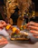 A smiling woman enjoying a colorful skewer dish at La Broqueta's rustic wooden table.