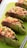 Several green tea-flavored bread rolls are filled with a mixture of scrambled eggs or tofu, diced cucumbers, and chopped red bell peppers. The rolls are arranged neatly on a bright green cutting board with a perforated white surface visible on the side.