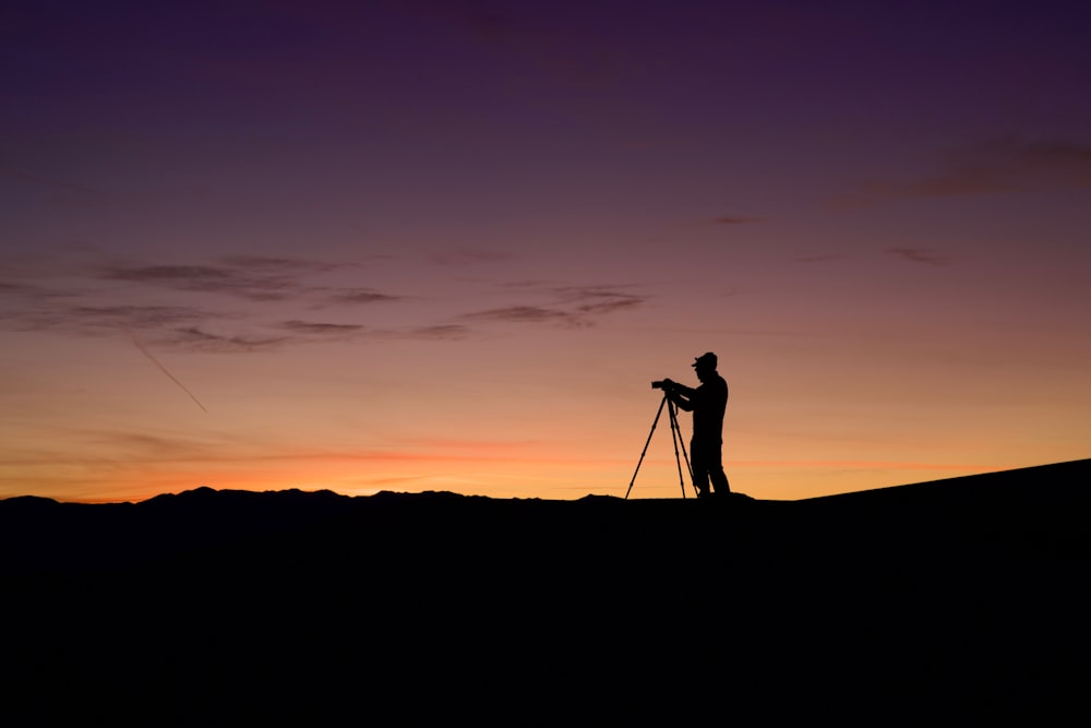 eine Person, die mit einer Kamera auf einem Hügel steht