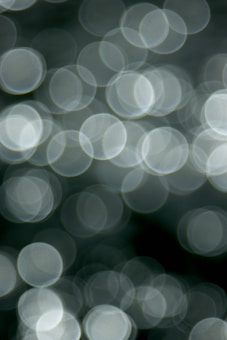 A blurred background with overlapping circular light spots, creating a bokeh effect with a soft focus and smooth texture.