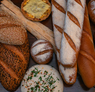 An assortment of breads including seeded loaves, baguettes, and rustic rolls artfully arranged on a linen cloth.