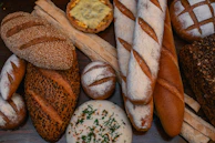 Display of assorted breads with textures of seeds, crusts, and golden hues.
