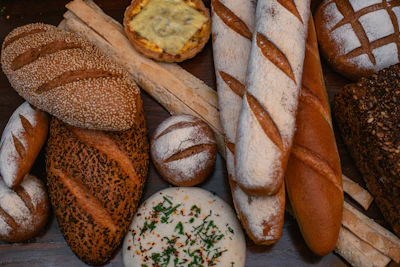An assortment of breads including seeded loaves, baguettes, and rustic rolls artfully arranged on a linen cloth.