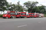 A fleet of cargo vehicles lined up on a quiet urban road.