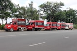 A fleet of trucks lined up, each showcasing different brand advertisements in a sunny parking lot.