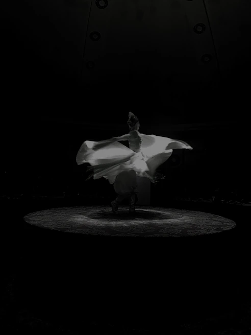 A dancer performing an elegant LED show with swirling lights illuminating the stage.