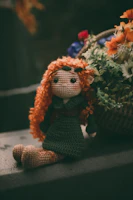 Handmade crochet dolls with delicate details sitting on a warm orange fabric background