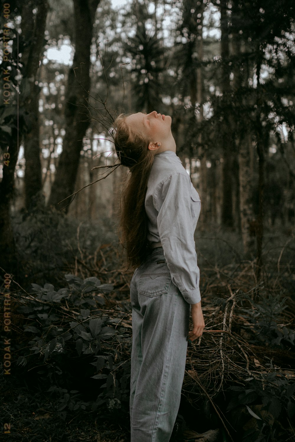 a woman with long hair standing in the woods