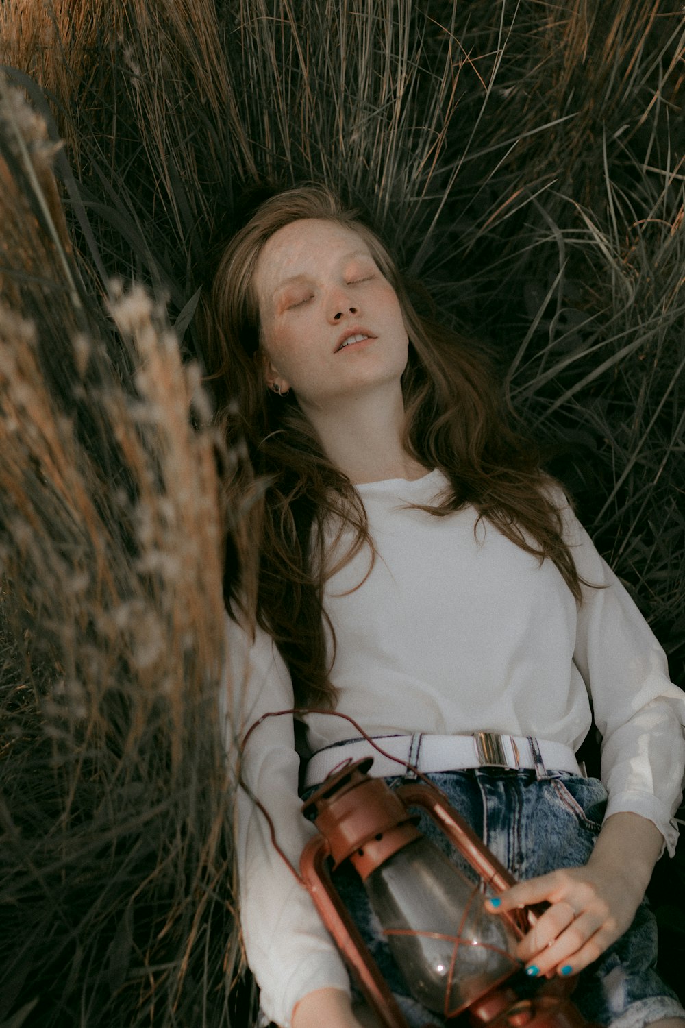 a young girl laying in the grass with her eyes closed