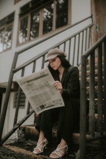 a woman sitting on the steps reading a newspaper