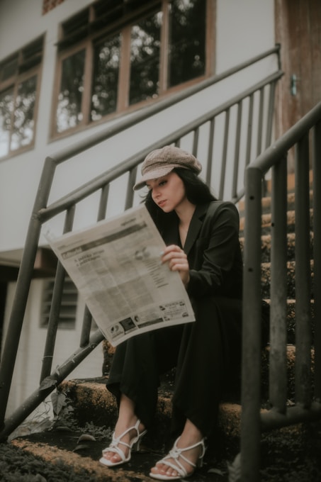 a woman sitting on the steps reading a newspaper