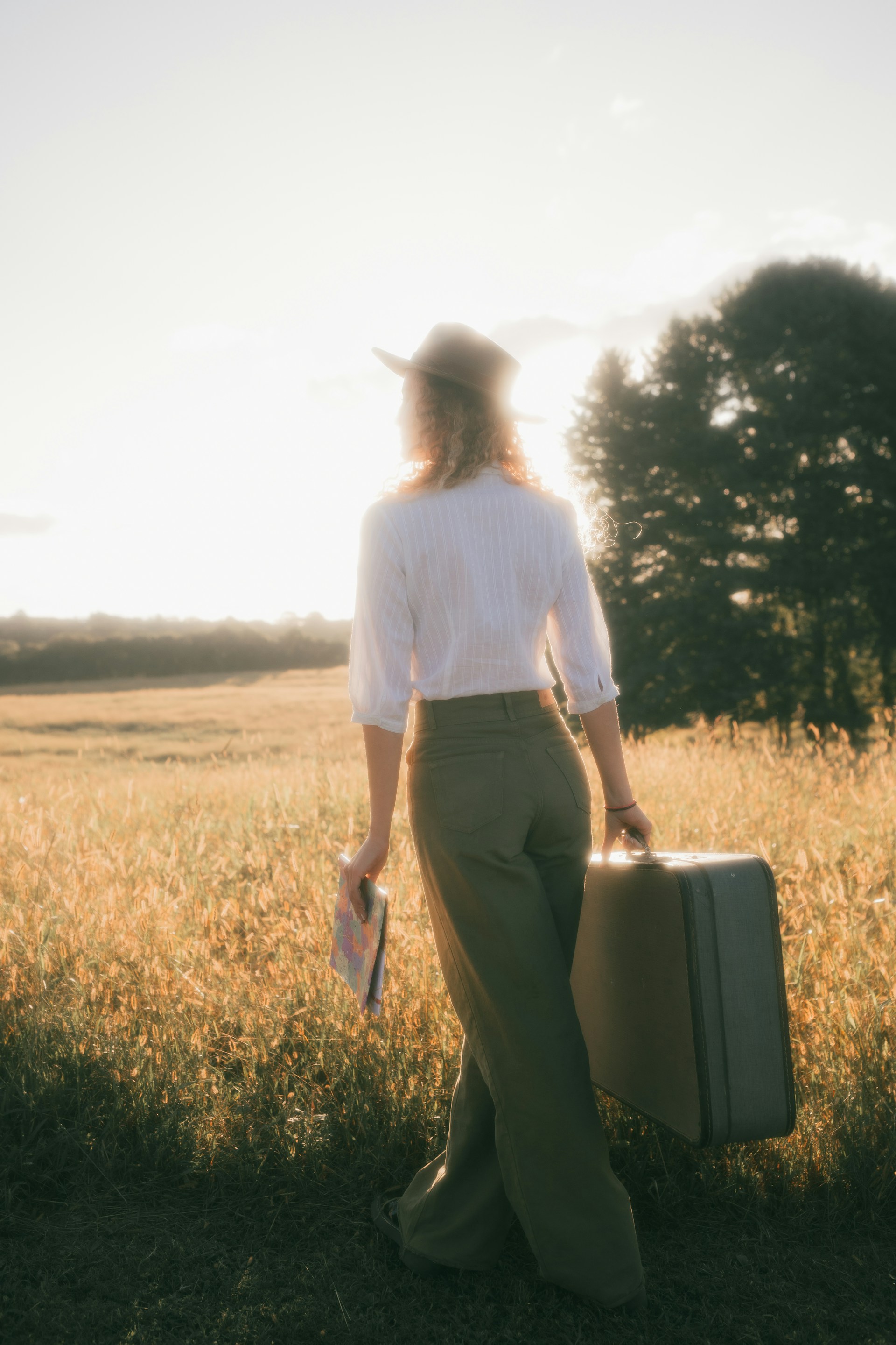 a woman holding a suitcase in a field