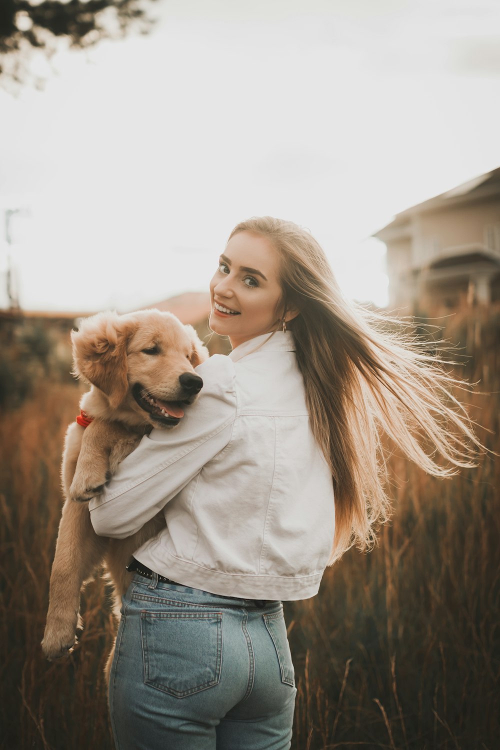 a woman holding a dog in a field