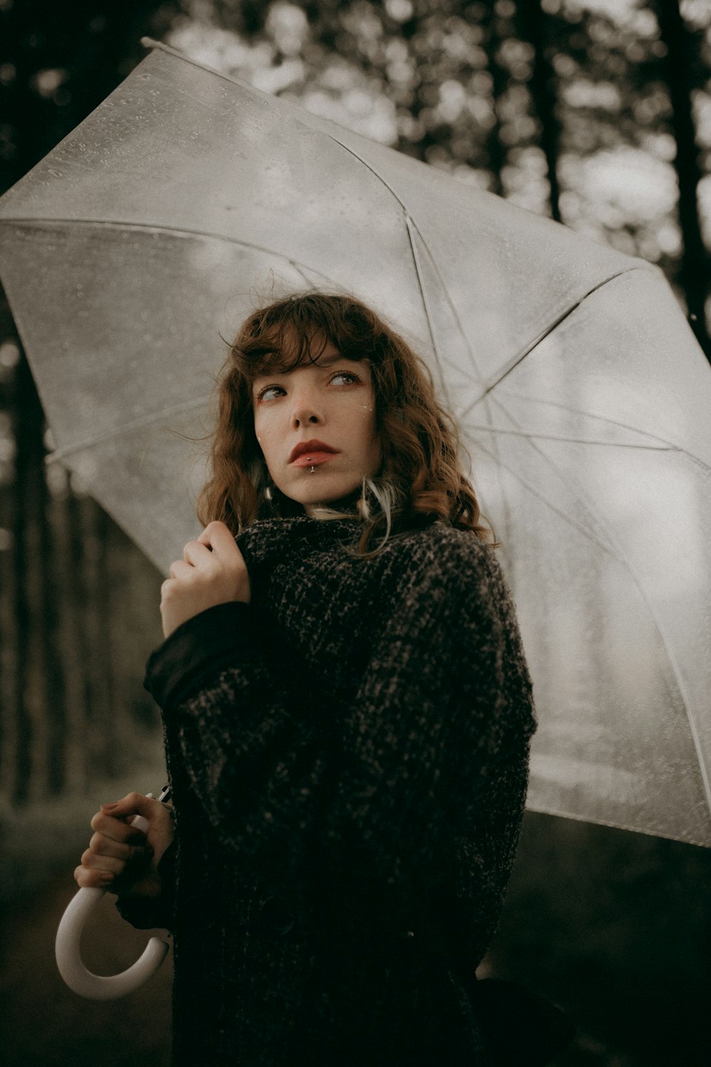 a woman holding an umbrella in a forest