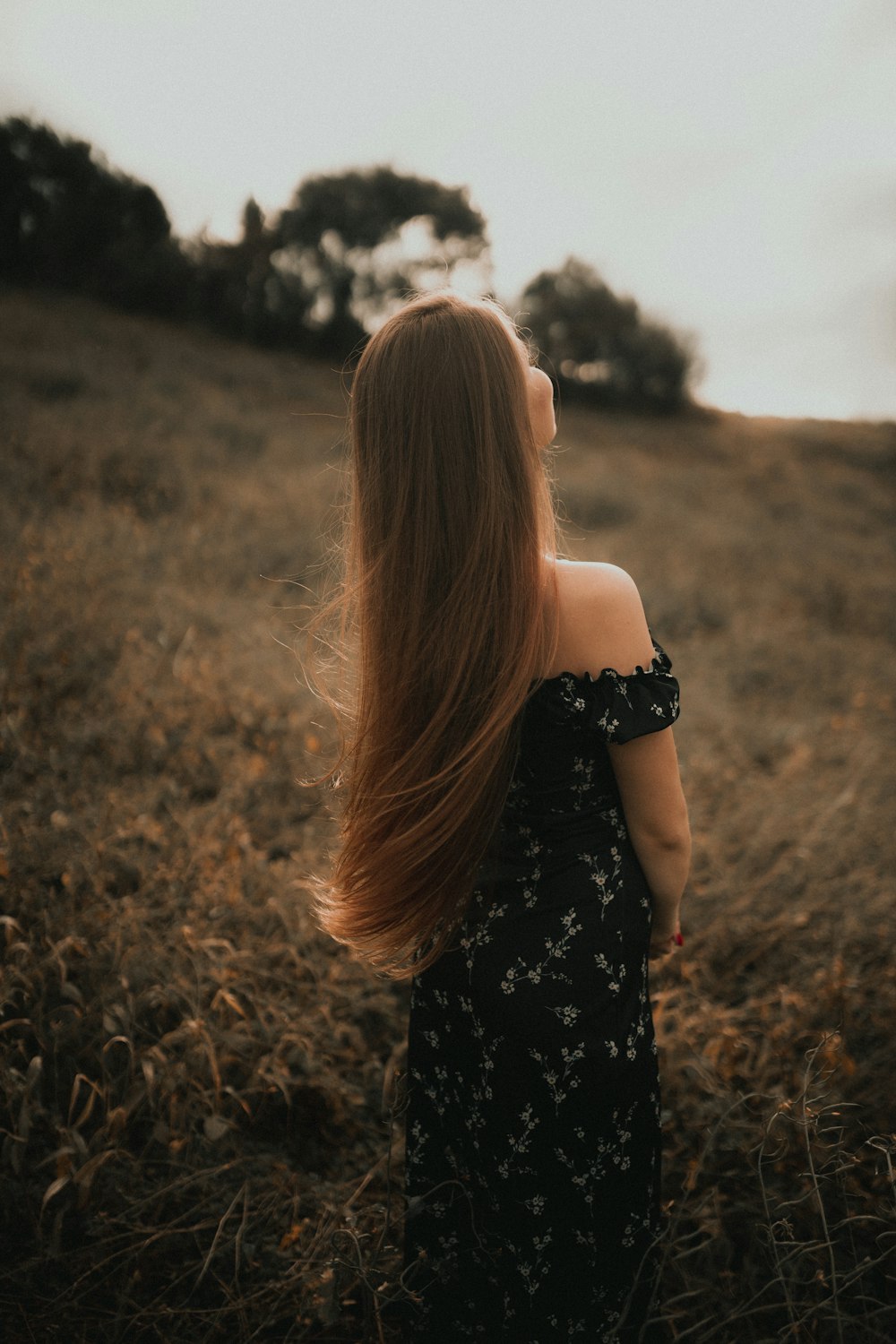 a woman with long hair standing in a field