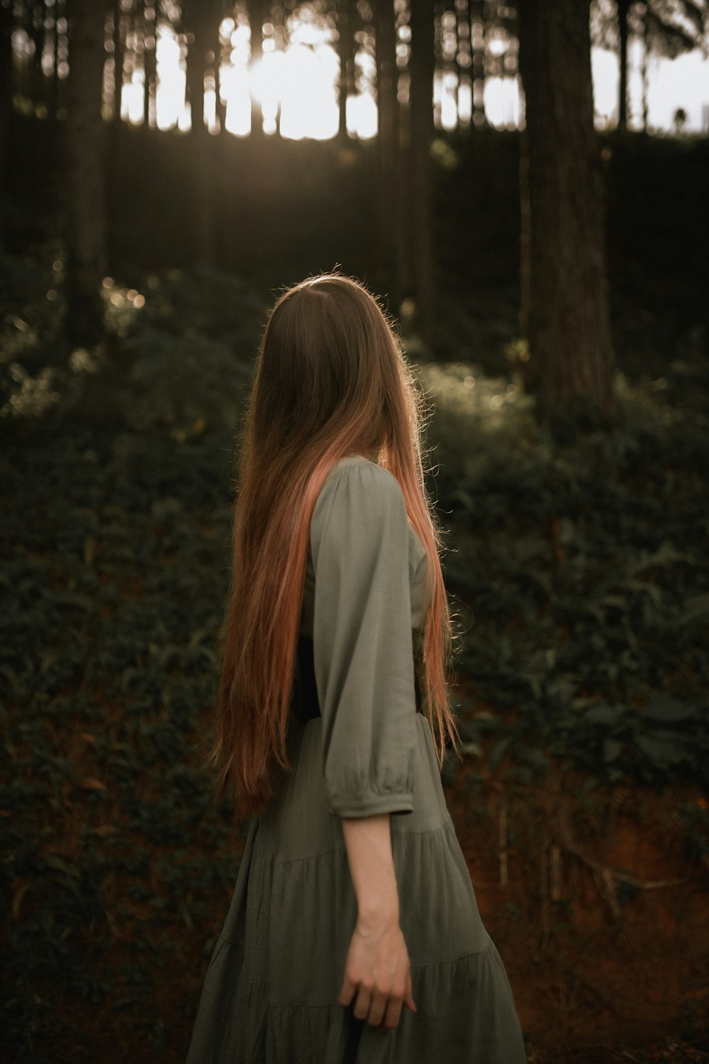 a woman with long red hair walking through a forest